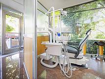 Behandlungszimmer mit gelber Ausstattung und großen Glasfenstern