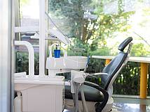 Behandlungsstuhl vor großen Glasfenstern